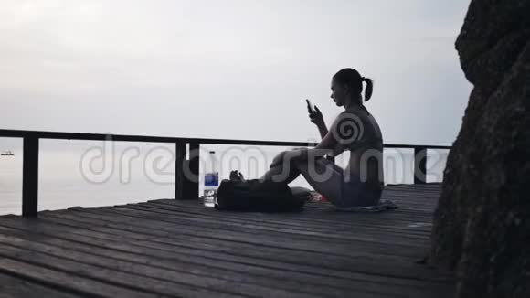 带着智能手机在码头旅行的女孩视频的预览图