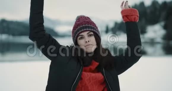 快乐又漂亮的年轻女士戴着一顶红色的帽子在冬天的日子里在大自然面前跳舞玩得开心视频的预览图