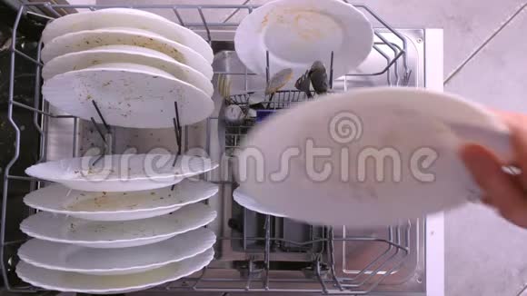 男人手把白色的脏盘子和勺子放在洗碗机里用厨房用具推篮子视频的预览图