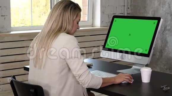 商务女性穿着衣服坐在靠近窗户的工作场所在办公室里使用电脑绿屏模拟显示视频的预览图