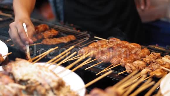 厨师使用烹饪刷子将酱汁放在鸡肉和猪肉串上动作缓慢街头市场上美味的肉类食品视频的预览图