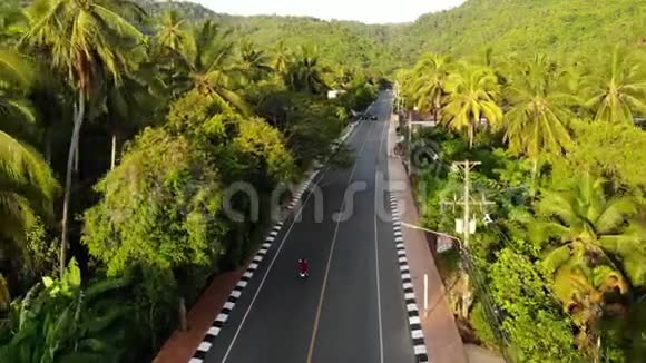 沥青路穿过聚落和丛林沥青道路穿过典型的小聚落和绿色热带视频的预览图