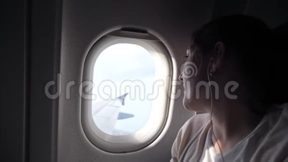 年轻女子的肖像正在看飞机窗户视频的预览图