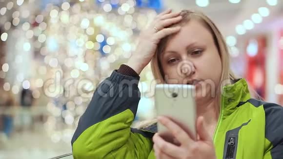 一个女人直着头发看着智能手机站在一个购物中心背景是一个视频的预览图