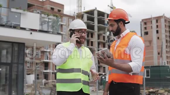 幸福工程师在施工现场用手机讲话检查工人工作情况建筑商会谈视频的预览图