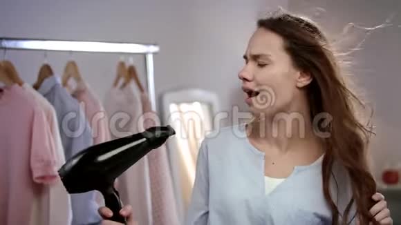 快乐的女人在吹风机里唱歌情绪化的女人在浴室唱歌视频的预览图