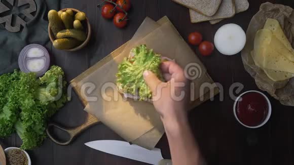 用培根和沙拉片做三明治时厨师在木板上的三明治里加入沙拉然后做视频的预览图