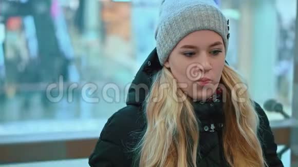迷人的年轻女孩戴着冬帽坐在电梯里在商场里视频的预览图