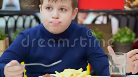那个男孩在咖啡馆里吃薯条和肉丸用苏打水清洗视频的预览图