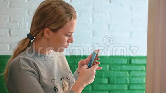 漂亮女孩站在服装店的试衣间里用智能手机做镜子自拍视频的预览图