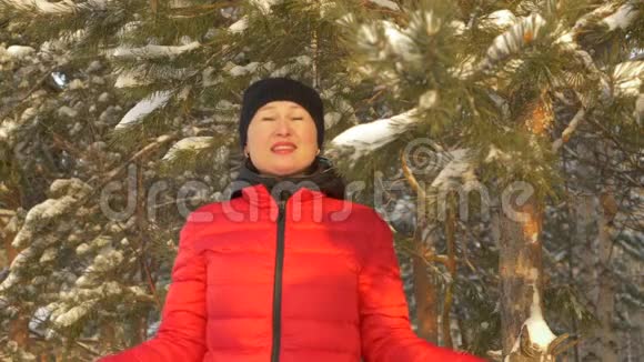 在冬天的森林里幸福的女人站在雪下慢动作视频的预览图
