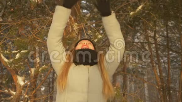 快乐的小女孩在冬天的雪林中跳跃在树上漫步视频的预览图