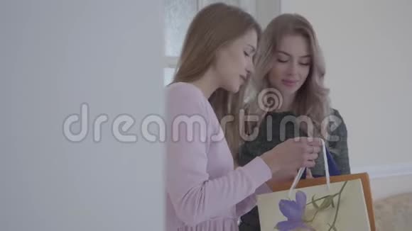 年轻的女人带礼物给她的朋友他们看着包里紧紧地拥抱着两个女朋友在一起视频的预览图