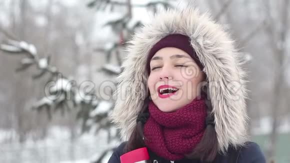 美丽的年轻女孩在浪漫的心情微笑等待她的男朋友在一个冬季公园视频的预览图