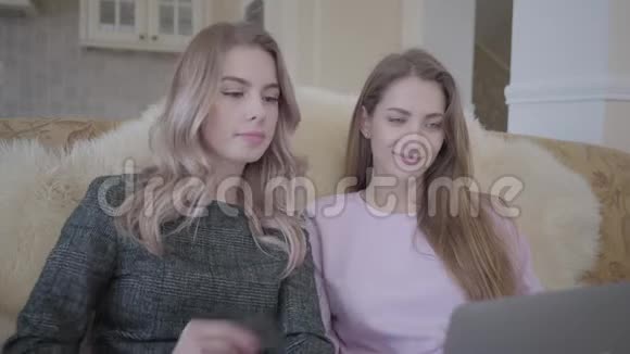两位年轻漂亮的女朋友正在用笔记本电脑上网寻找优惠折扣视频的预览图