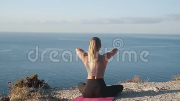 女性在垫子上练习瑜伽早晨冥想慢动作的背面视图视频的预览图