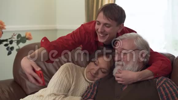 可爱的祖父母和他们有趣的孙子正在自拍看着智能手机相机微笑着玩得很开心视频的预览图