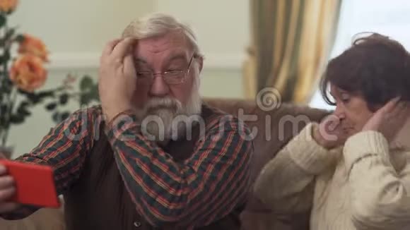 成熟的夫妇在手机上自拍老人纠正他的头发他的妻子坐得更近进步休闲视频的预览图