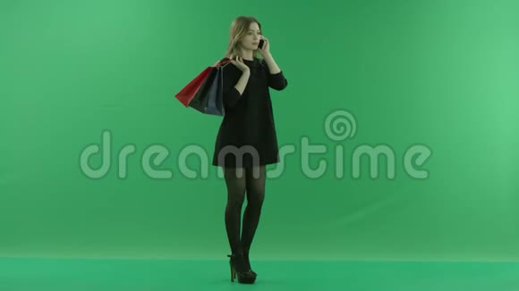 年轻貌美的女士在买完智能手机后肩上背着一个包背着绿色的钥匙背景视频的预览图