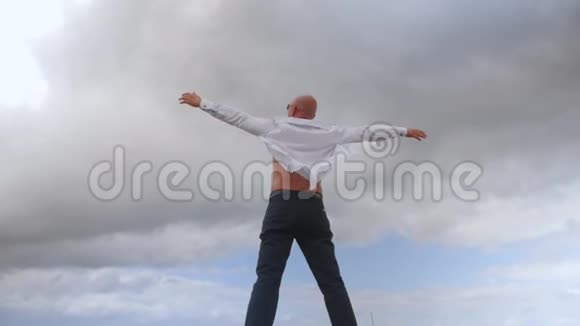 人站在云天背景下展开双臂的后景中弹视频的预览图