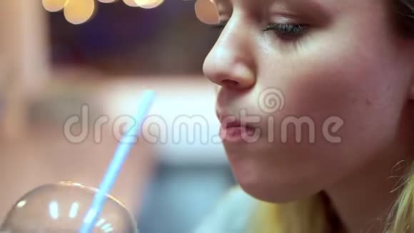 少女从管子里喝柠檬水她在快餐店里视频的预览图