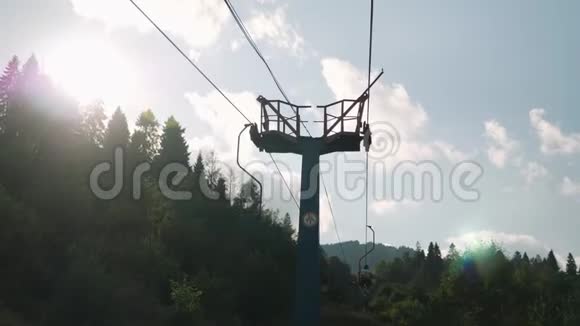 用钢缆在蓝天和绿树上抬椅子夏季在喀尔巴阡山举行的椅子升降活动视频的预览图
