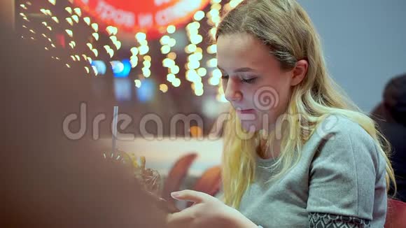 年轻的少女写智能手机信息她正在咖啡馆里吃晚饭快餐晚上在视频的预览图