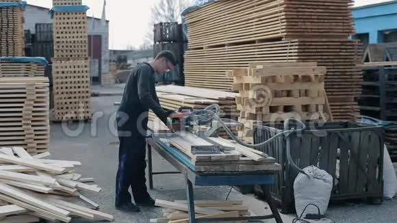 工业青年木工使用木切割机人切木木板视频的预览图