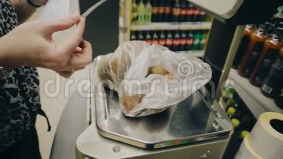 这个女孩正在购物中心秤上称土豆并把它贴在印在t上的土豆标签上视频的预览图