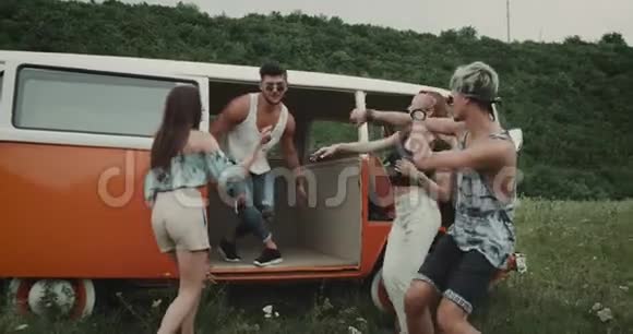 一群年轻的朋友在大自然中快乐地跳舞在复古的货车里和草地上视频的预览图