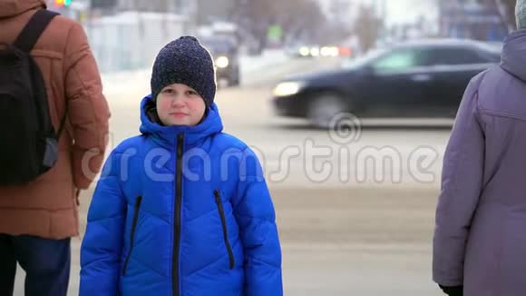 穿着蓝色羽绒服的少年站在街上汽车在后台男孩在看视频的预览图