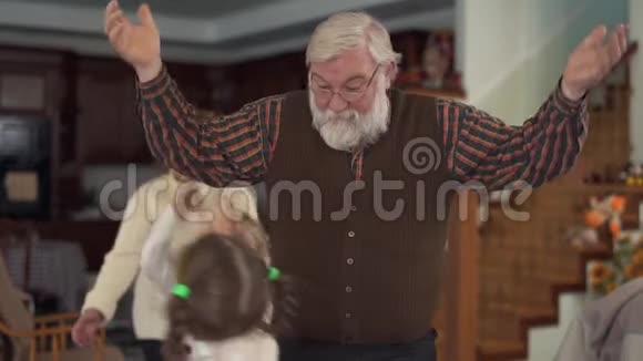 老人和他的孙子在客厅里玩得很近祖父举起双手两个女孩抓住他视频的预览图