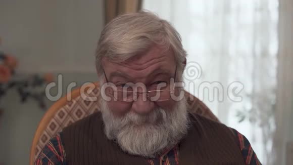 一位带着微笑的成年祖父的肖像他留着一个大胡子长着一副戴着眼镜坐在摇椅上的英俊模样视频的预览图