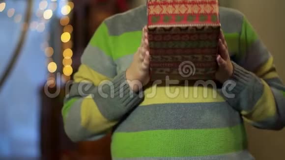 特写男生的手穿毛衣的青少年送礼物在圣诞灯的背景下视频的预览图