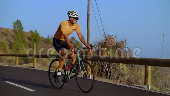 一个穿黄色T恤的男人骑着自行车骑在山蛇上视频的预览图