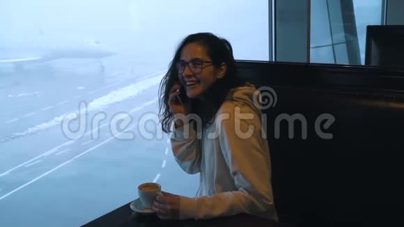 带咖啡的女孩在机场休息室打电话视频的预览图