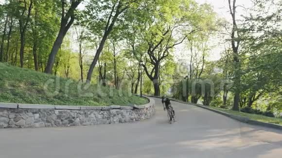 强壮的运动自行车手从马鞍上向上坡冲刺骑自行车的人穿着黑色运动服视频的预览图
