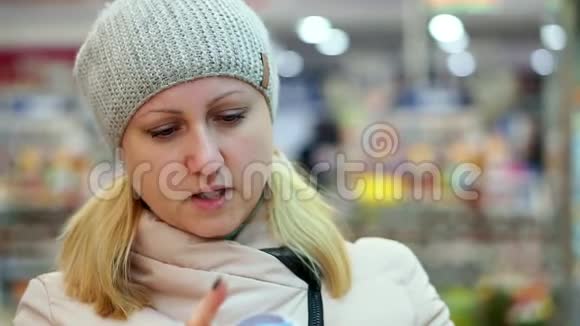 一个穿着冬天衣服的女人在超市里读一罐食物上的课文她把罐子放在架子上视频的预览图