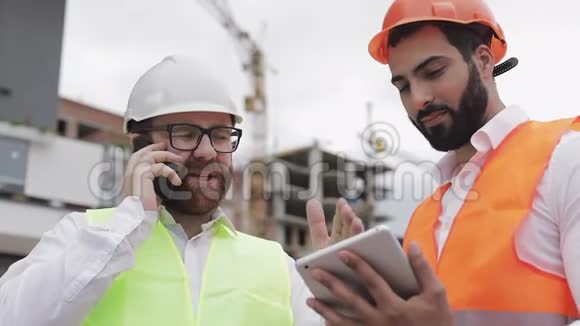 幸福工程师在施工现场用手机讲话检查工人工作情况建筑商会谈视频的预览图