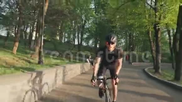 强壮的运动自行车手从马鞍上向上坡冲刺骑自行车的人穿着黑色运动服慢动作视频的预览图
