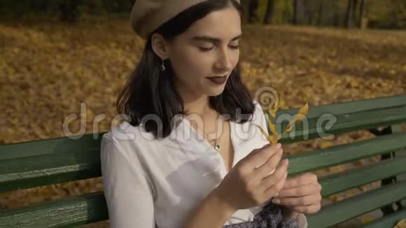 滑稽浪漫的贝雷帽女人透过树叶看太阳秋天公园4K视频的预览图