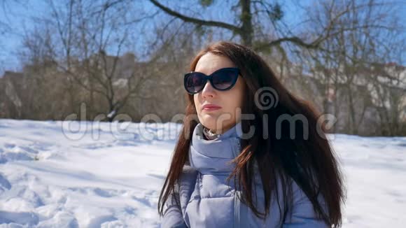 年轻女子戴着黑色太阳镜和直发在阳光明媚的早晨在公园里享受户外活动但视频的预览图