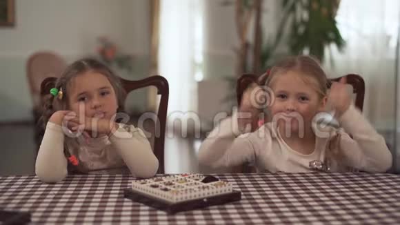 两个辫子可爱的女孩坐在厨房的桌子旁那盒糖果站在桌子上姐妹吃视频的预览图