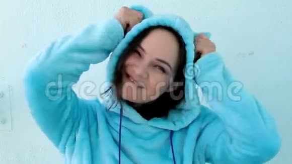 穿着蓬松的蓝色睡衣或猫装的可爱黑发女人摸着头罩上的服装耳朵视频的预览图