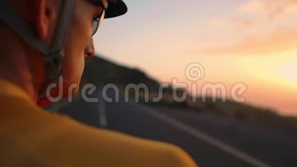 男人脸骑着黄色衬衫的骑自行车的人看着夕阳健身后休息熨斗视频的预览图