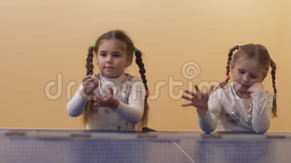 两个梳着辫子的漂亮小女孩在玩乒乓球闲的幸福姐妹慢动作视频的预览图