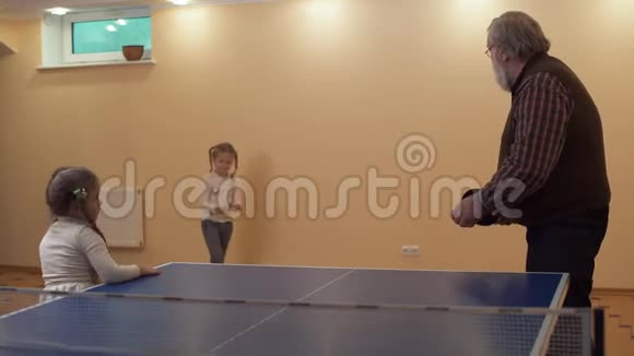 孙女给她祖父一个球靠近网球桌他正在准备第一次打击慢慢视频的预览图