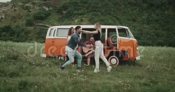 野餐时的杂技元素跳舞的情侣一些朋友在弹吉他坐在复古的货车上视频的预览图