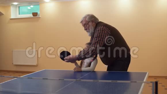 爷爷教他可爱的小孙女打网球帮她打一拳慢动作视频的预览图