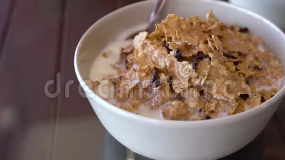 美味的早餐勺子混合玉米片和巧克力块在一个碗与牛奶慢动作视频的预览图